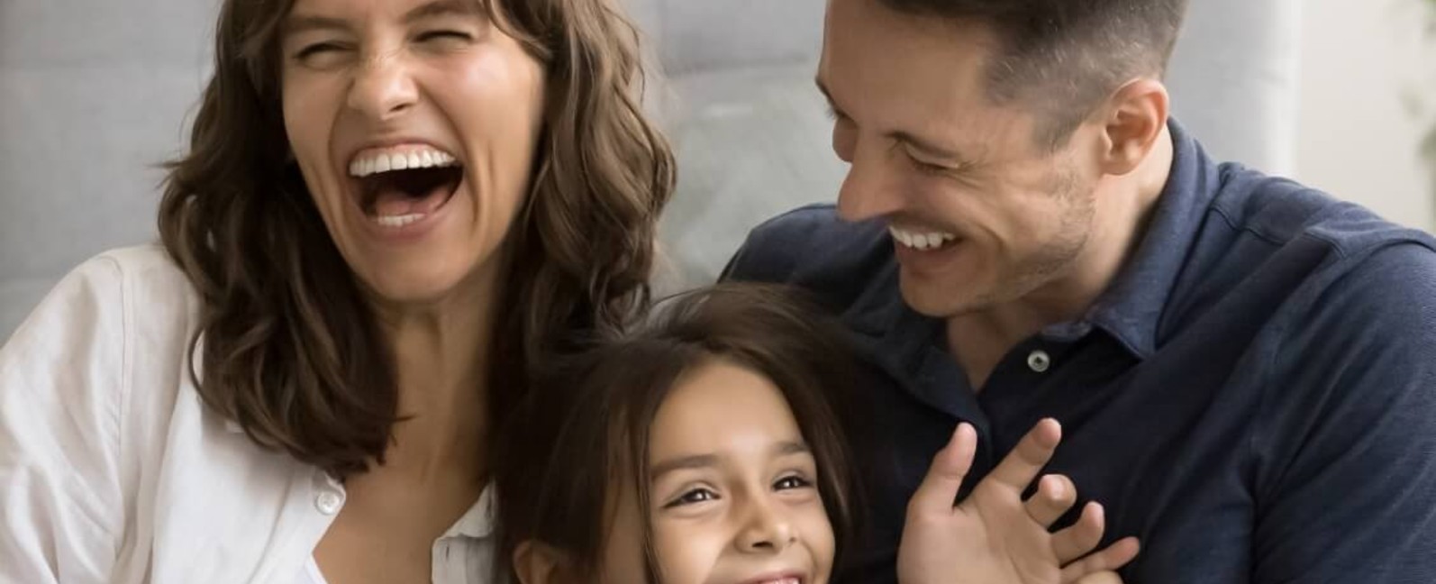 Parents laughing with their young daughter at home, kids' oral habits blog 1